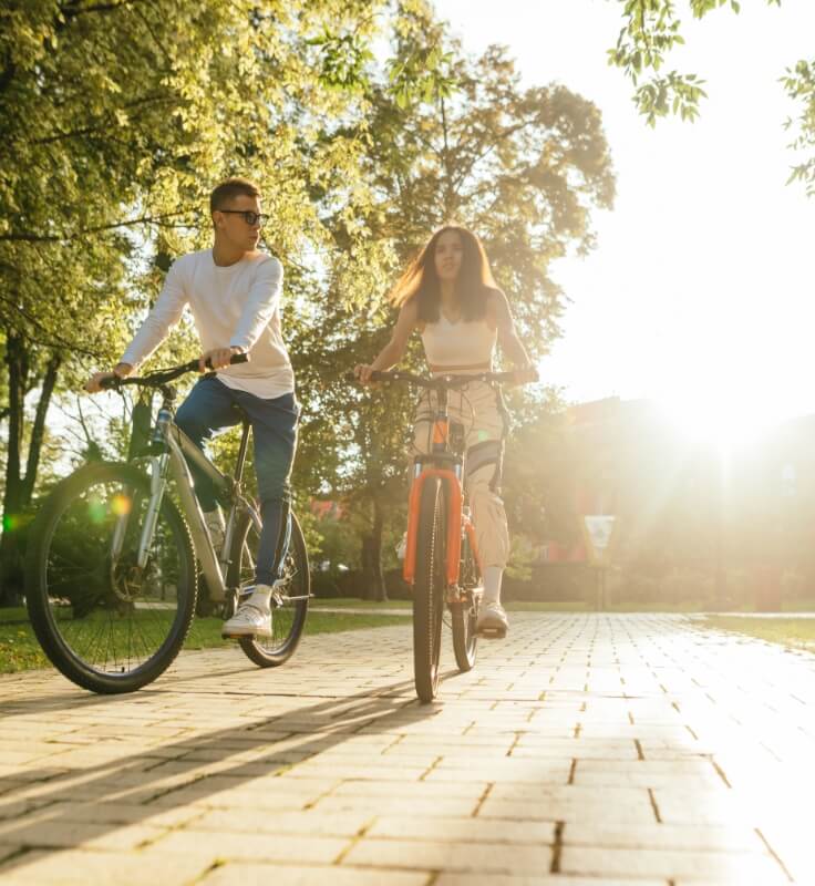 a couple biking down a path in the park