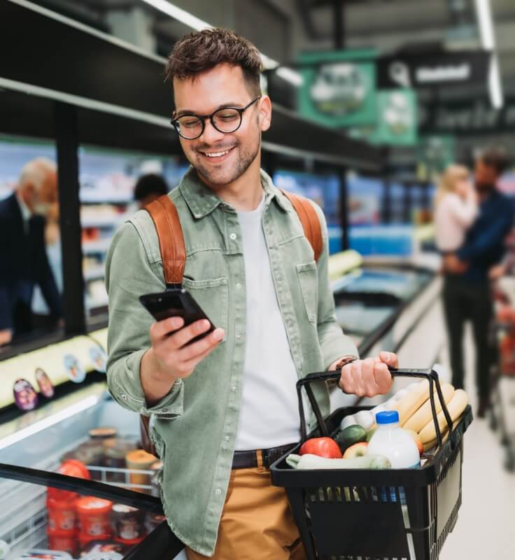 a young man shopping at a grocery store, checking his phone