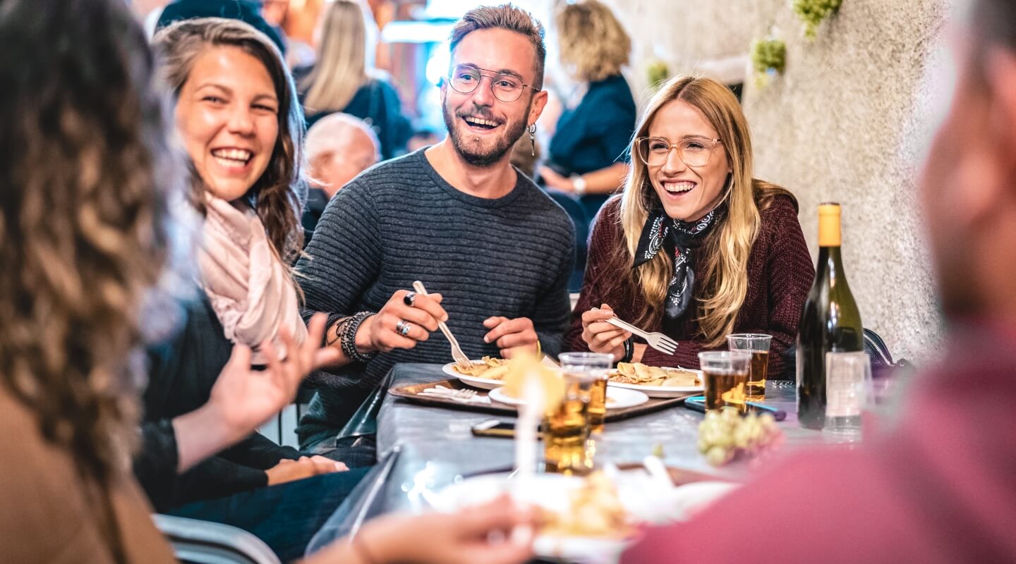 a group of young adults out to dinner, eating and drinking.